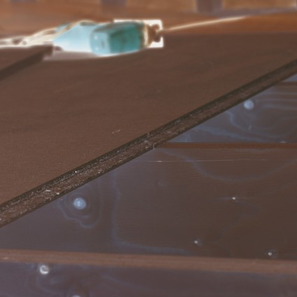 Skivmaterial monterat på träbjälkar, röd elektrisk såg i bakgrunden.