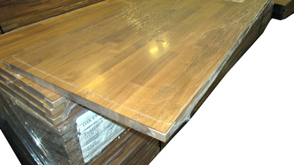 Ekbänkskivor staplade på varandra och inplastade, med träets ådring synlig.