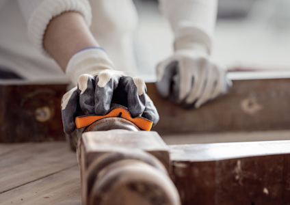 Händer med handskar arbetar med träramar på ett bord.