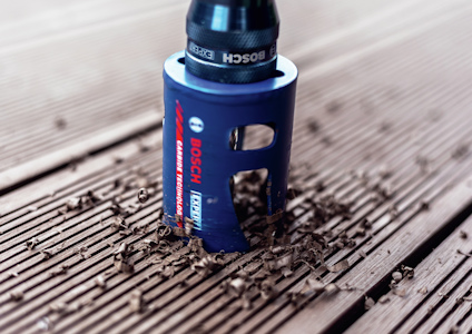 Hålsåg från Bosch med blå kropp borrar i trä, omgiven av träspån.