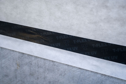 Svart byggtejp med texten "T-FLEX UV" på grått underlag.