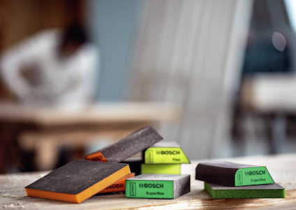 Slipblock från Bosch i olika färger och kornstorlekar märkta "Fine" och "Superfine" på ett träbord.