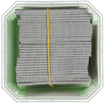 En låda fylld med packade metallspikband bundna med ett gummiband.