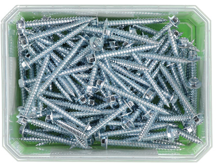 Låda med silverfärgade skruvar med brickor, huller om buller på en grön botten.