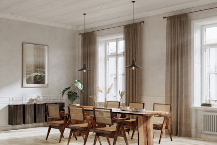 Ljust vardagsrum med träbord och stolar, bruna gardiner och takhängda lampor. Växter och konstverk på väggarna.
