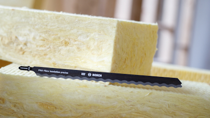 Svart sågklinga med text "PRO Fibre Insulation precise BOSCH" placerad på gul glasfiberisolering.